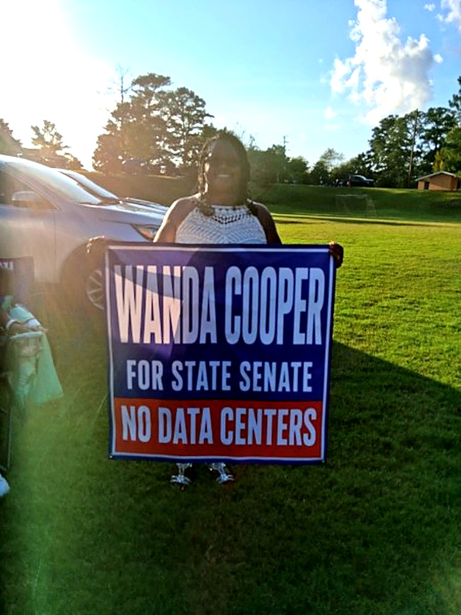 Supporter with a Wanda Cooper for State Senate sign at sunset
